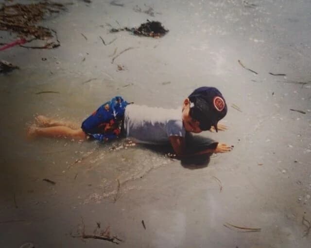 Daniel as a child sliding across shallow water