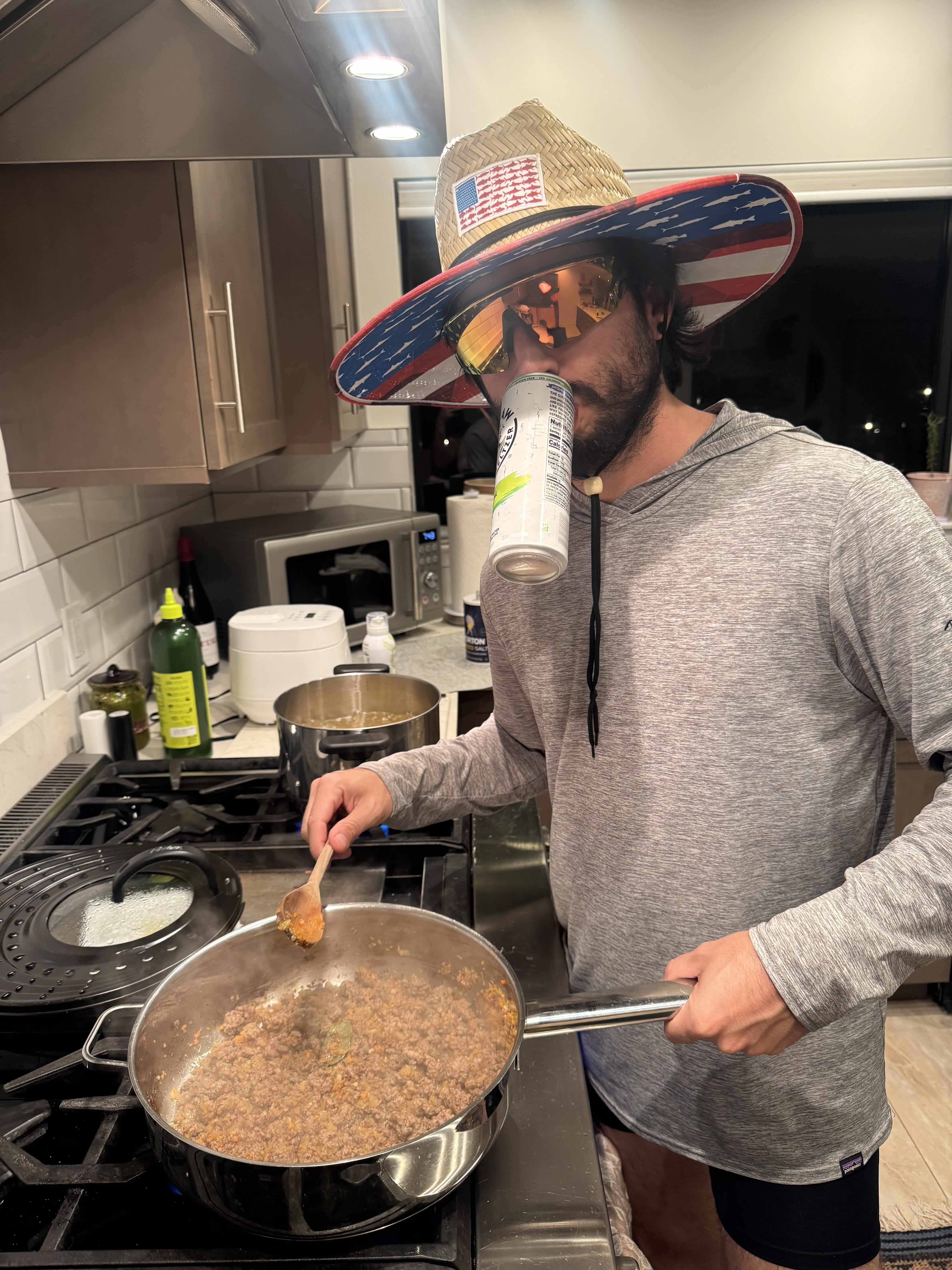 Daniel cooking in a kitchen while wearing a wide-brim hat